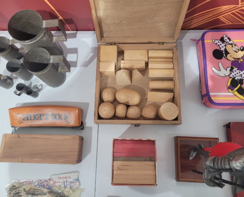 Caja de madera abierta con cuerpos geométricos de madera: cubos, prismas, pirámides, esferas, cilindros y conos.
